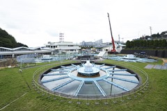緑の芝生に囲まれた浄水場施設内に、中心から放射状に青い仕切りが伸びた巨大な円形の沈殿池が複数並んでいる国見浄水場の写真