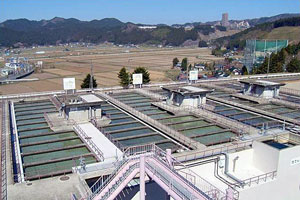 田園風景を見渡す高台に、コンクリートで区切られた細長い沈でん池が管理用の通路に囲まれて複数並んでいる写真