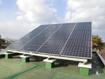 建物屋上の基礎の上に架台を組み、傾斜をつけて設置された1基のソーラーパネルがある安養寺配水所太陽光発電設備の写真