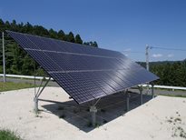 緑豊かな林を背景とした敷地内に1基の大型ソーラーパネルが傾斜をつけて設置されている、福岡浄水場太陽光発電設備の写真