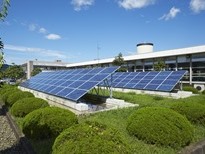 丸く整えられた植栽に囲まれた緑豊かな敷地内に、傾斜をつけて並べられた2基の太陽光発電用ソーラーパネルが設置されている、茂庭浄水場太陽光発電設備の写真