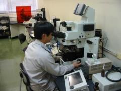 検査室で作業服を着た男性職員が大型の顕微鏡を覗き込みながら水質検査を行っている様子の写真