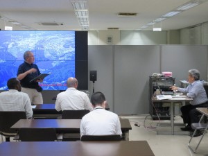 地図が投影された大型スクリーンを前に男性が説明を行い、席に座った派遣研究員の方々が講義に耳を傾けている、東北工業大学今野名誉教授による講義の様子写真