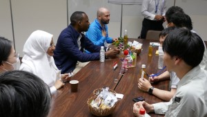 お菓子や飲み物が置かれたテーブルを囲み、日本人職員と派遣研究員の方々が会話をしている、懇談の様子写真