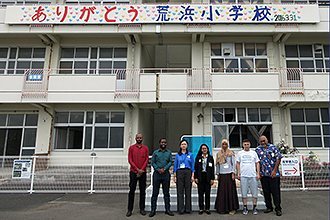 「ありがとう 荒浜小学校」と書かれた横断幕が掲げられた校舎の前に派遣研修員が一列に並んで撮影した、震災遺構荒浜小学校見学の記念写真
