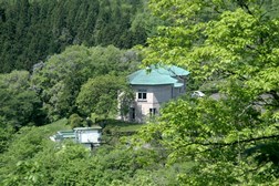 深い緑に包まれた山あいに緑色の屋根を持つ水道記念館が建ち、周囲を豊かな樹木が取り囲む写真